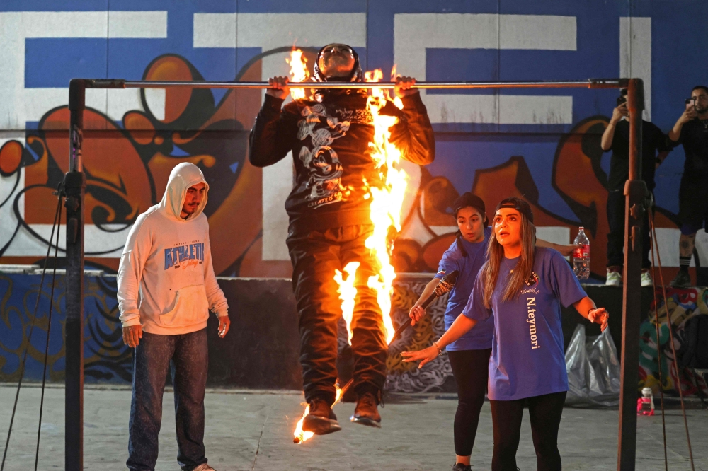 Iranian coach and stunt woman Nasrin Teymouri (R) teaches fire techniques to stunt performers Mojgan Nematollahi (C) and Arshia Teymouri (L) during a training session in in Tehran's skatepark, in the capital on September 25, 2026. — AFP pic