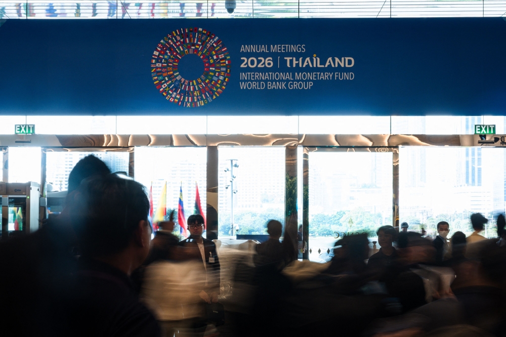 People walk past a display bearing the logo of the 2026 IMF-World Bank Group Annual Meetings during preparations for the event at the Queen Sirikit National Convention Centre in Bangkok, Thailand, on October 9, 2026. — AFP pic