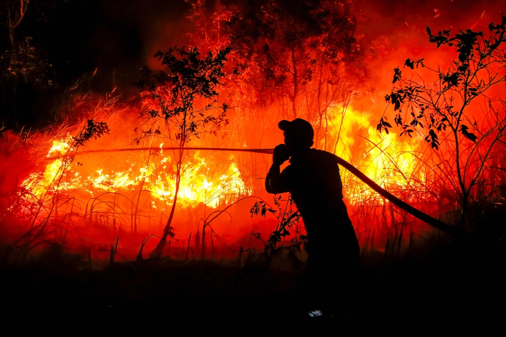 A firefighter from the Regional Disaster Management Agency douses a forest fire at Sungai Rambutan village in Ogan Ilir, South Sumatra on September 11, 2026. — AFP pic