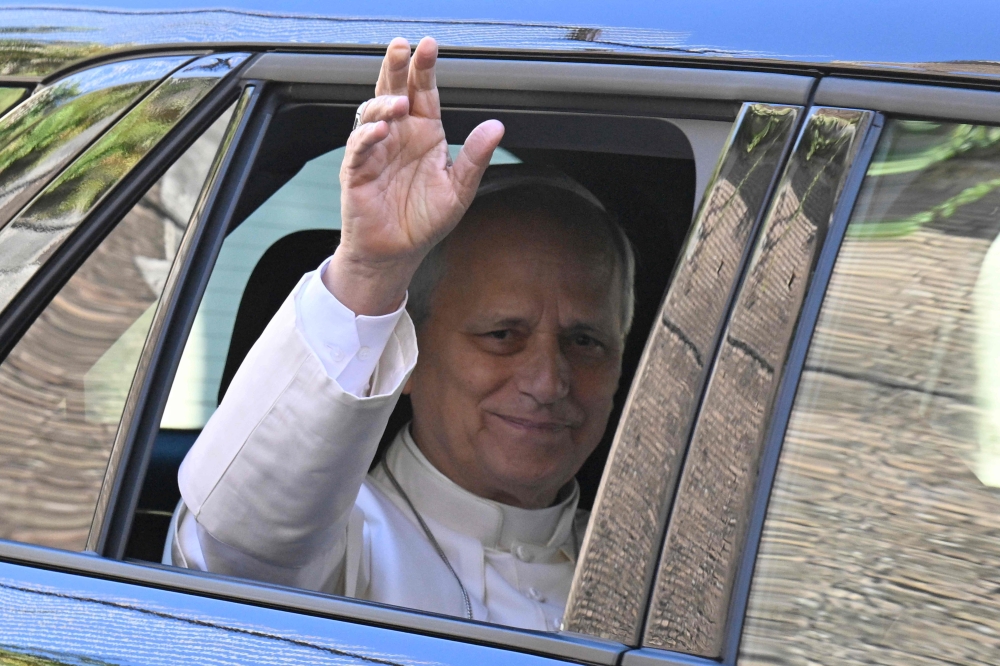 Pope Leo XIV waves from the window of the car as he leaves the Vatican before being admitted to Rome’s Gemelli University Hospital for an operation to remove a lump from his lung, in the Vatican on 13 October 2026. — AFP pic