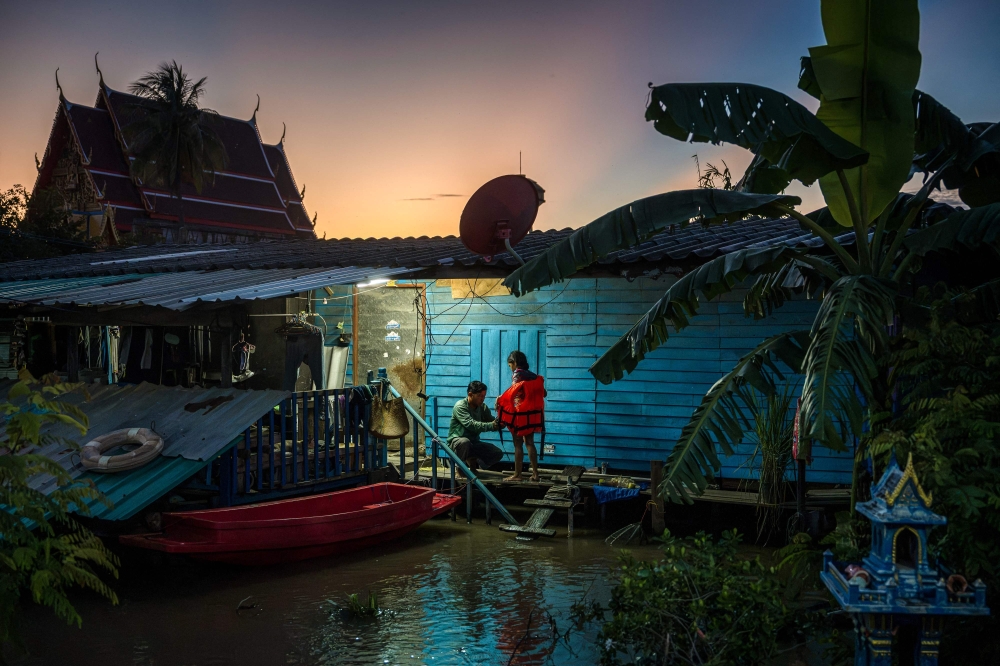 A father removes a flotation vest worn by his daughter in front of their flooded home in Bang Ban district in the central Thai province of Ayutthaya on October 7, 2026. — AFP pic