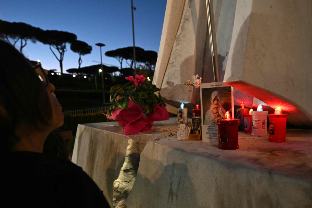 Candles, flowers and prayers are led at the statue of John Paul II outside Rome’s Gemelli University Hospital, where Pope Leo XIV has been admitted for an operation to remove a lump from his lung October 13, 2026. — AFP pic