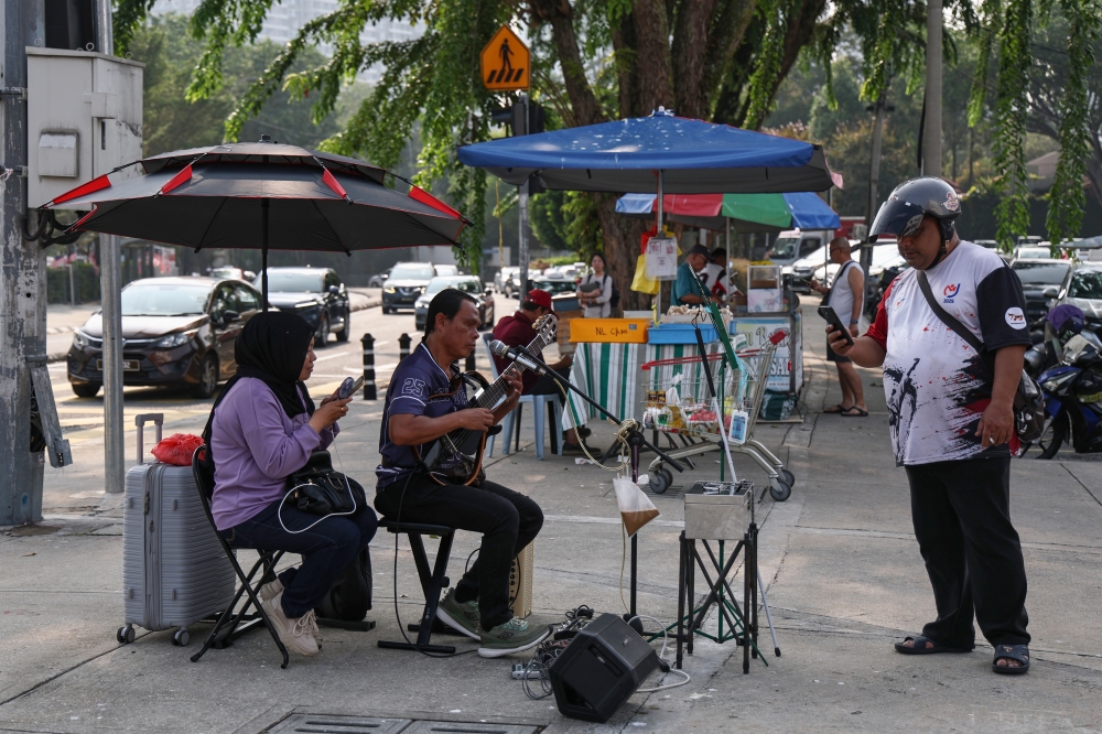 Rodie Jainahum performs with his visually impaired wife in Bangsar, one of the few locations where the couple can now busk regularly. — Bernama pic