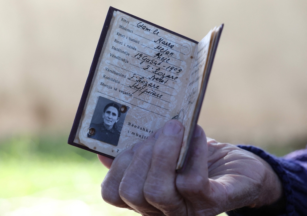 Qamile Marra shows an identity document from Albania's communist era during an interview. — AFP pic
