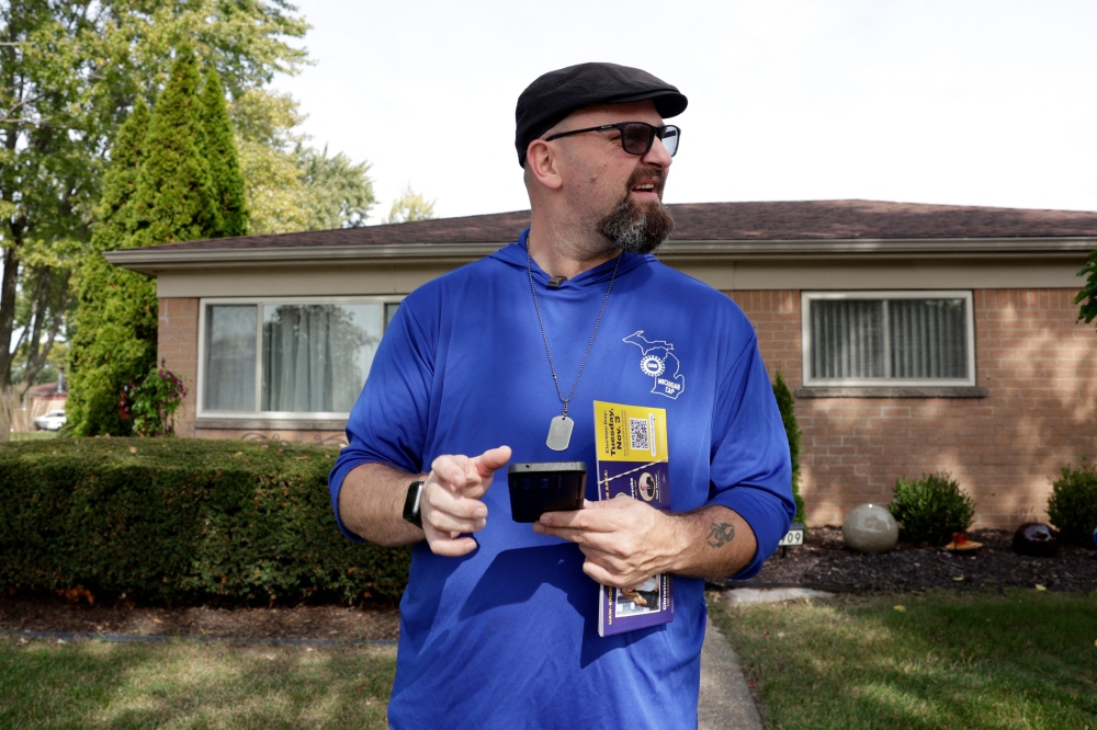 United Auto Workers union member Rob Banks walks between homes to promote the union’s preferred slate of candidates for the upcoming midterm elections in Warren, Michigan, on October 10, 2026. — AFP pic