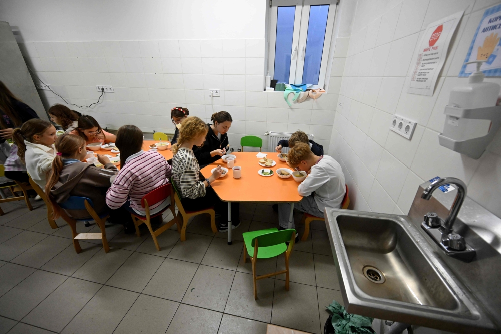 Schoolchildren eat lunch in the canteen of a shelter located in the basement of UMKA Primary School during an air raid alert in the suburbs of Kyiv on October 20, 2026, amid Russia’s invasion of Ukraine. — AFP pic