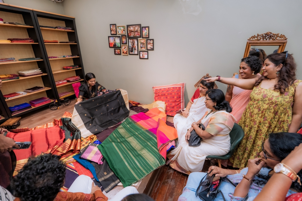 Jeevitha (centre, in a black floral saree) unfold pure Kanjivaram silk for saree enthusiasts during an open day celebrating 14 years of preserving the heritage of silk sarees. The session proved an educational one, with guests leaving in awe of these handwoven masterpieces.