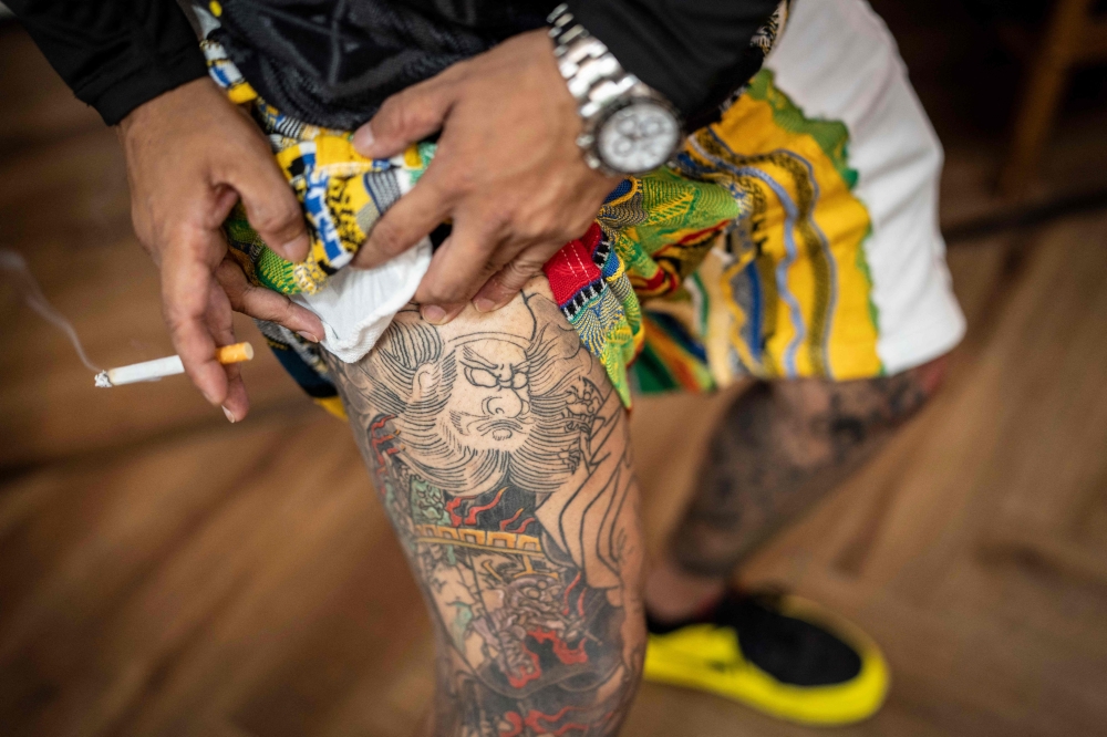 This photo taken on August 27, 2026 shows Tekisasu, an active yakuza gangster allied to a major clan, showing his tattoos on his leg at a barbershop in Tokyo. — AFP pic