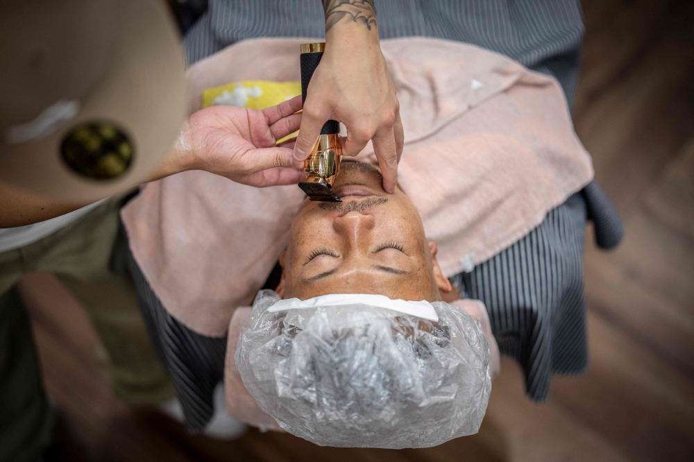 This photo taken on August 27, 2026 shows Tekisasu, an active yakuza gangster allied to a major clan, having his beard trimmed at a barbershop in Tokyo. — AFP pic