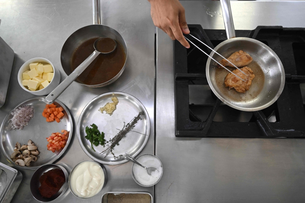 This photograph taken on September 22, 2026 shows a student chef preparing the classic French dish ‘Poulet sauté chasseur’ at the Ecole Ducasse, a French culinary school in Gurugram. — AFP pic