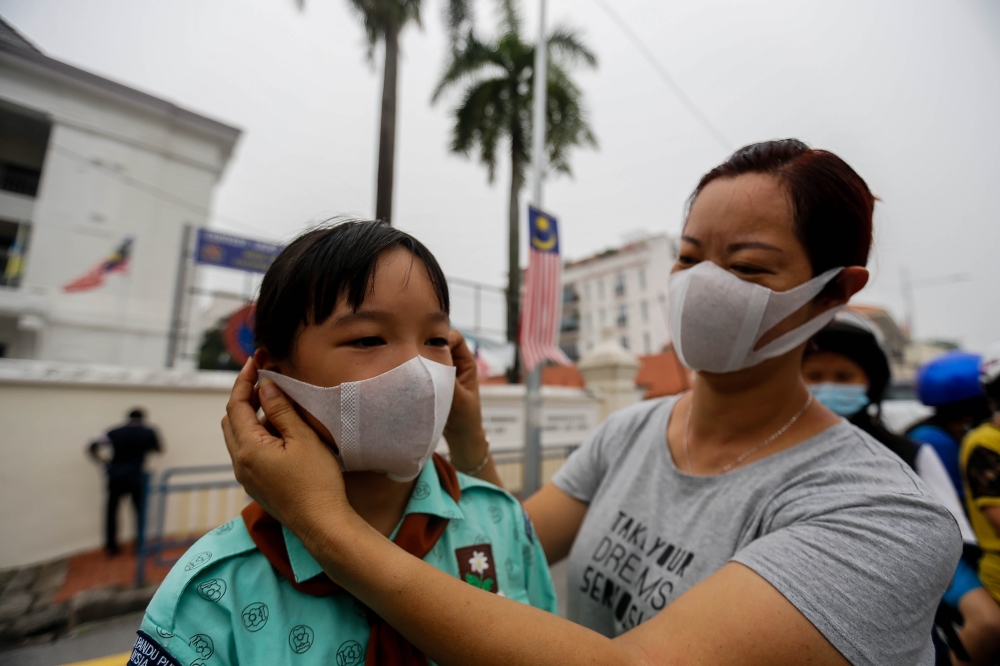 File picture of a mother helping her child put on a face mask. — Picture by Sayuti Zainudin