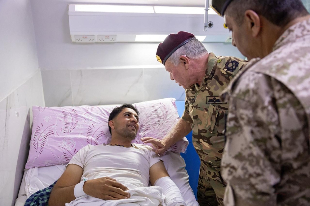 King Abdullah II (centre) speaks to one of the people injured at the Prince Ali Military Hospital in Karak, Jordan after gunmen attacked a church during a funeral on October 23, 2026. — Jordanian Royal Palace handout pic via AFP