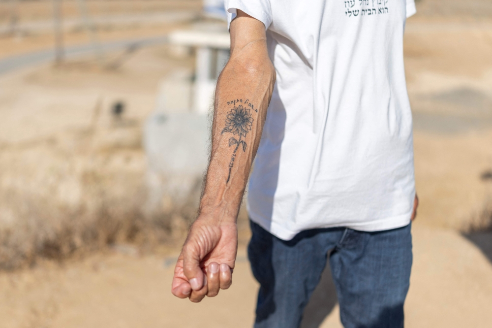 Danny, a Nahal Oz resident, shows his sunflower tattoo bearing the Hebrew words ‘The Way to Hope’, commemorating the October 7, 2023 Hamas attack, at the kibbutz near the Gaza border on October 22, 2026.  — AFP pic
