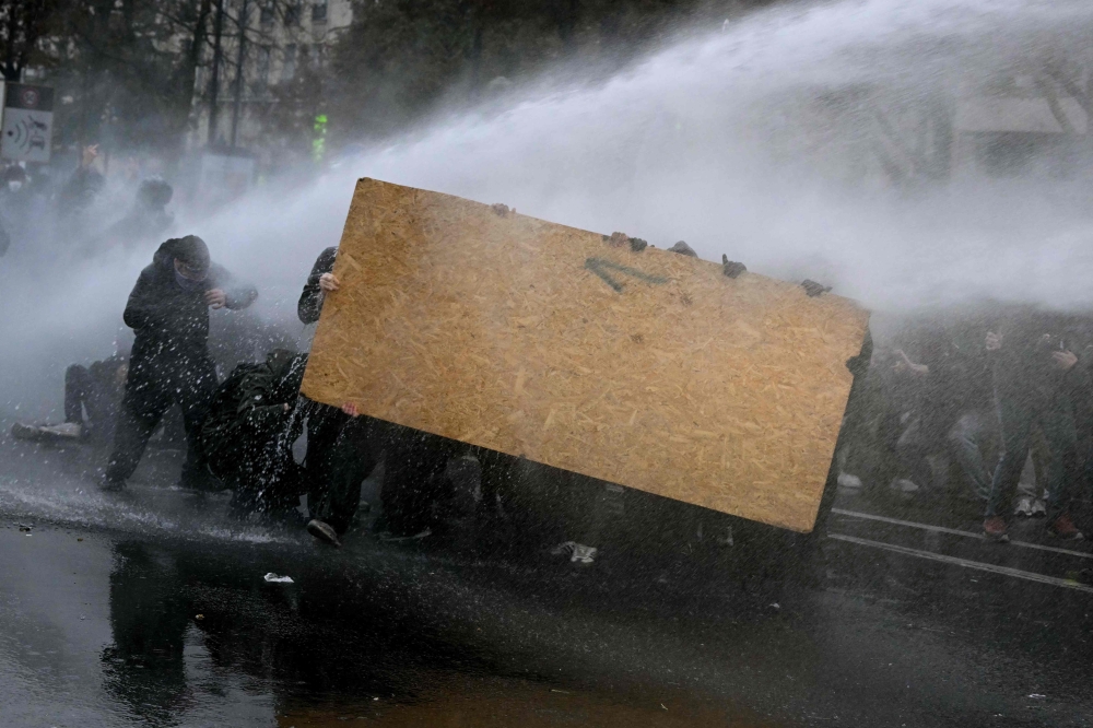 Protesters take shelter from a police water cannon near Porte de Vincennes during a nationwide demonstration over rising living costs and public services in Paris on October 24, 2026. — AFP pic
