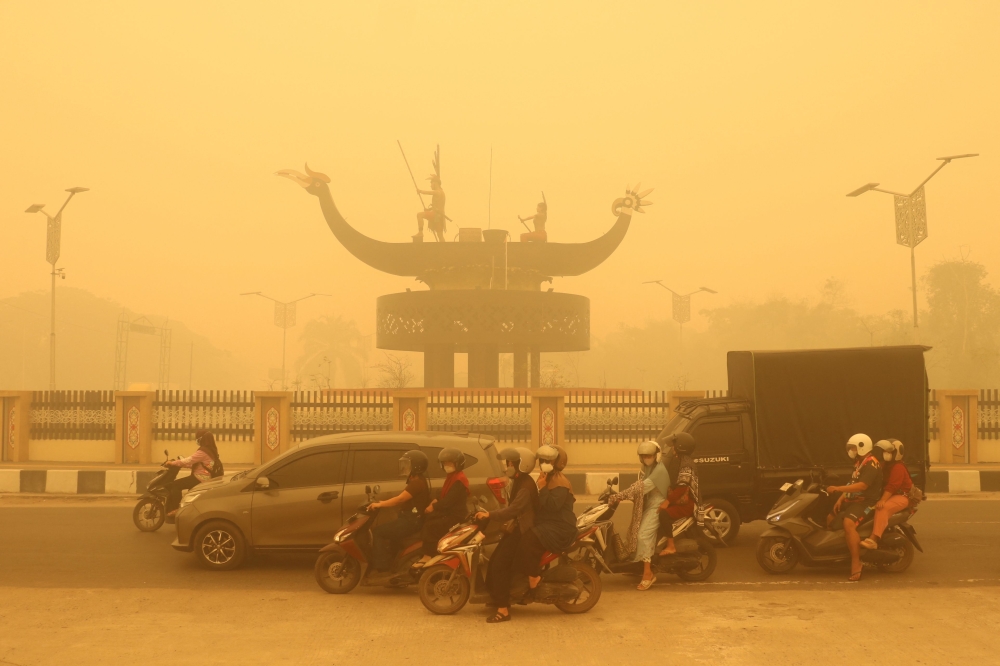 Motorcyclists wearing face masks ride amid thick haze from forest and land fires in Palangkaraya, Central Kalimantan on October 24, 2026. — AFP pic