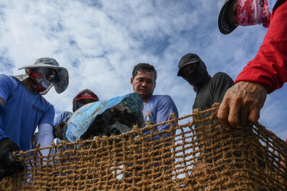 In this photo taken on October 13, 2026, workers fill coconut-fibre bags with oyster shells on a breakwater at Pamarawan Island in Malolos City, Bulacan province. — AFP pic