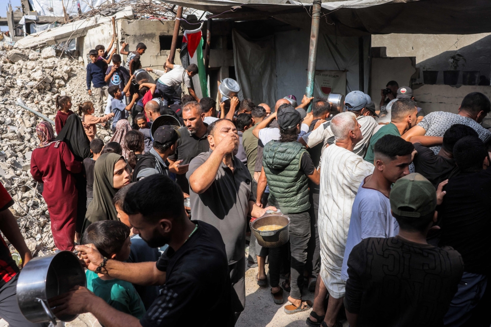 People wait to receive meals at a charity kitchen in the Jabalia camp for Palestinian refugees in the northern Gaza Strip on October 24, 2026. 