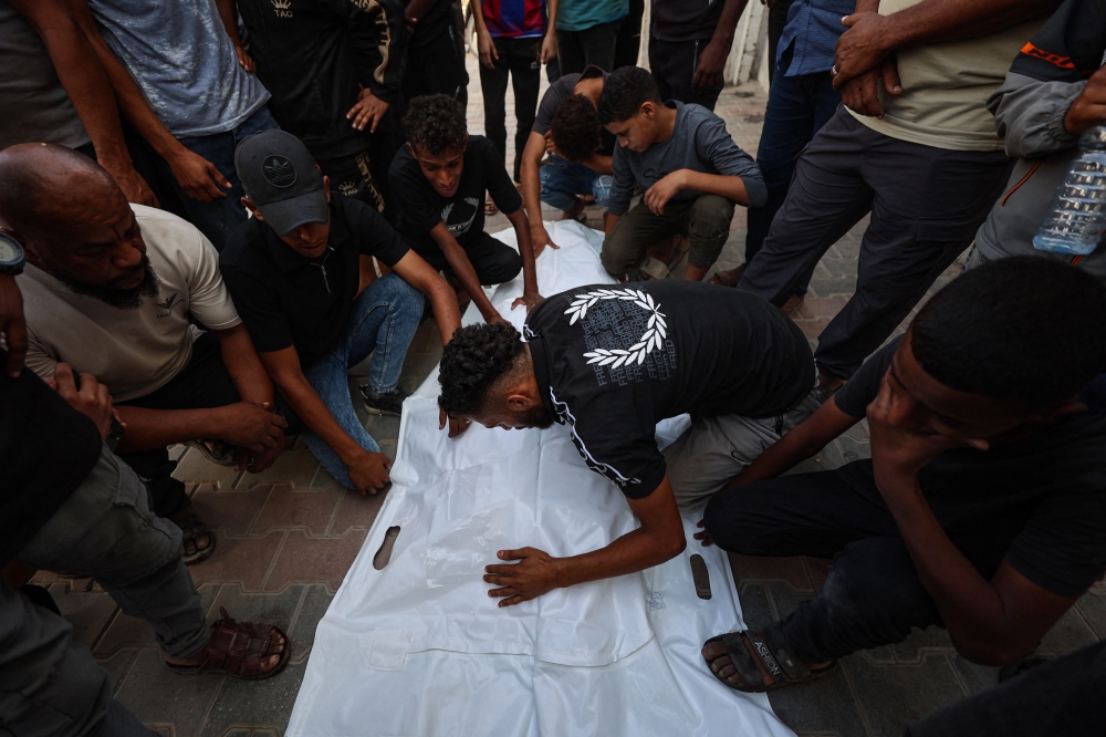 Mourners grieve over the bodies of three Palestinians during their funeral at Al Shifa Hospital in Gaza City on October 25, 2026, after they were killed in an Israeli strike on the Islamic University building.