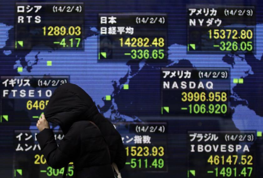 A pedestrian taking shelter from rain walks past an electronic board showing various countries' share prices outside a brokerage in Tokyo February 4, 2014. u00e2u20acu201d Reuters pic