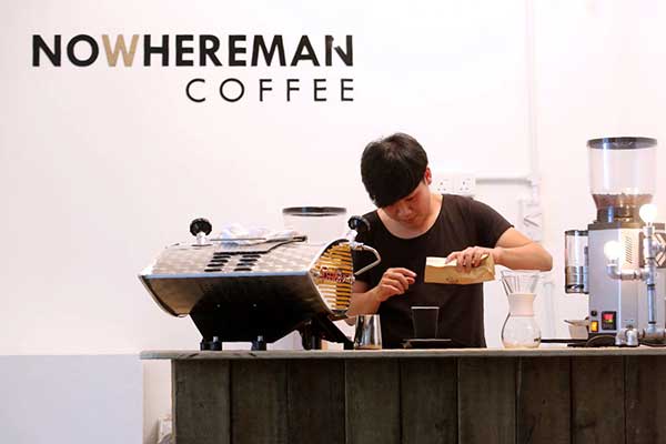 Mah uses a scale to carefully weigh coffee beans before grinding.