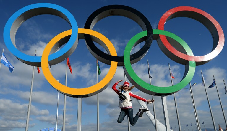 A woman jumps for a picture under the olympic rings on February 6, 2014 in the Olympic park before the start of the 2014 Sochi Winter Olympic Games.  u00e2u20acu201d AFP pic