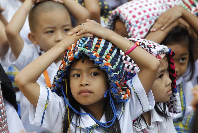 Elementary school pupils use doormats as improvised protective headgears as they stay in a safe area during an earthquake drill in Paranaque city, metro Manila February 10, 2014. u00e2u20acu201d Reuters pic