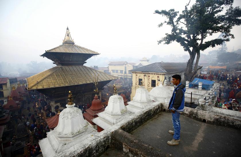 A man looks down at the Pashupatinath Temple as worshippers walk around scattering grains during the Bala Chaturdashi festival in Kathmandu December 2, 2013. u00e2u20acu201d Reuters pic