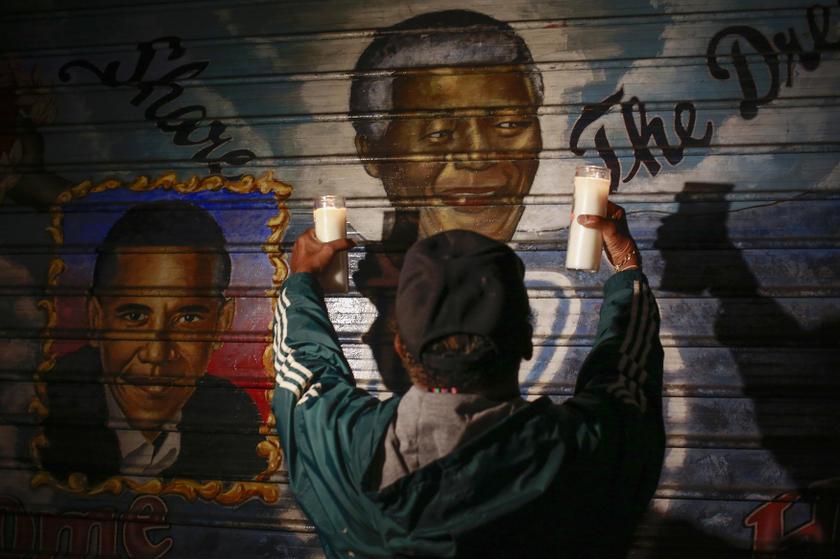 man holds candles in front of a mural of former South African President Nelson Mandela (centre) and US President Barack Obama in New York, December 5, 2013. u00e2u20acu201d Reuters pic
