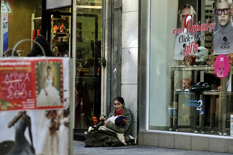 A woman holds her child as she begs outside shops displaying Christmas offers in central Athens on December 9, 2011. u00e2u20acu201d AFP pic