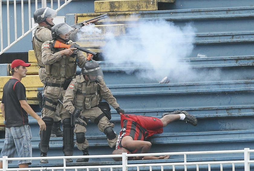 Policemen fire rubber bullets as they help an Atletico Paranaense fan during clashes between Vasco da Gama soccer fans and Atletico Paranaense fans at their Brazilian championship match in Joinville in Santa Catarina state December 8, 2013. u00e2u20acu201d Reuters pi