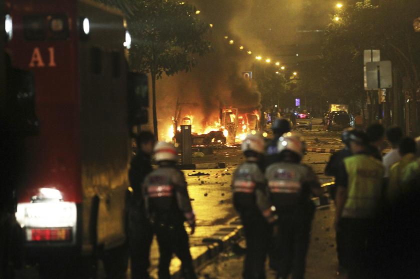 Riot policemen watch burning vehicles during a riot in Singapore's Little India district. December 9, 2013. A crowd set fire to vehicles and clashed with police in the Indian district of Singapore yesterday, in a rare outbreak of rioting in the city state