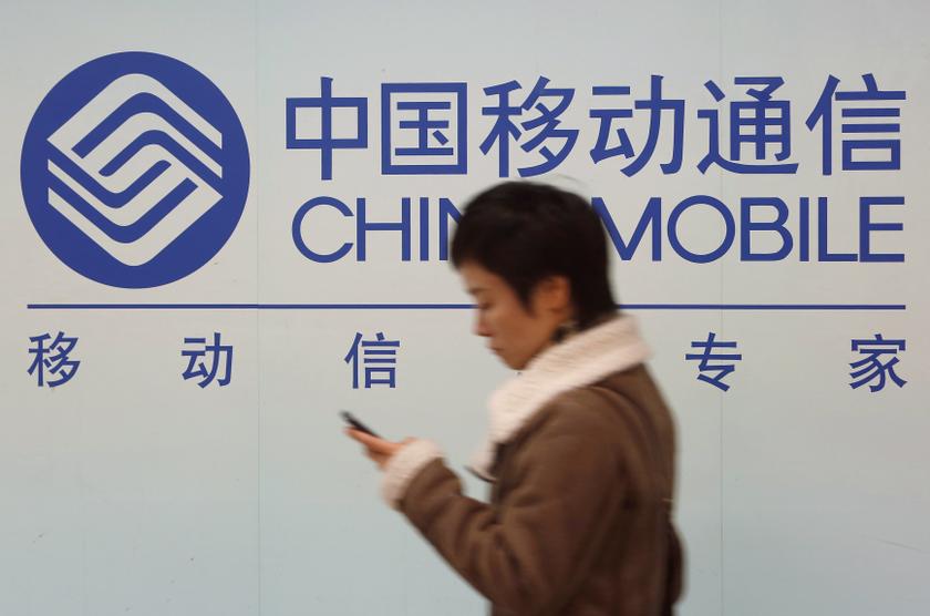 A woman looks at the screen of her mobile phone while walking past a China Mobile sign in downtown Shanghai December 18, 2013. u00e2u20acu201d Reuters pic