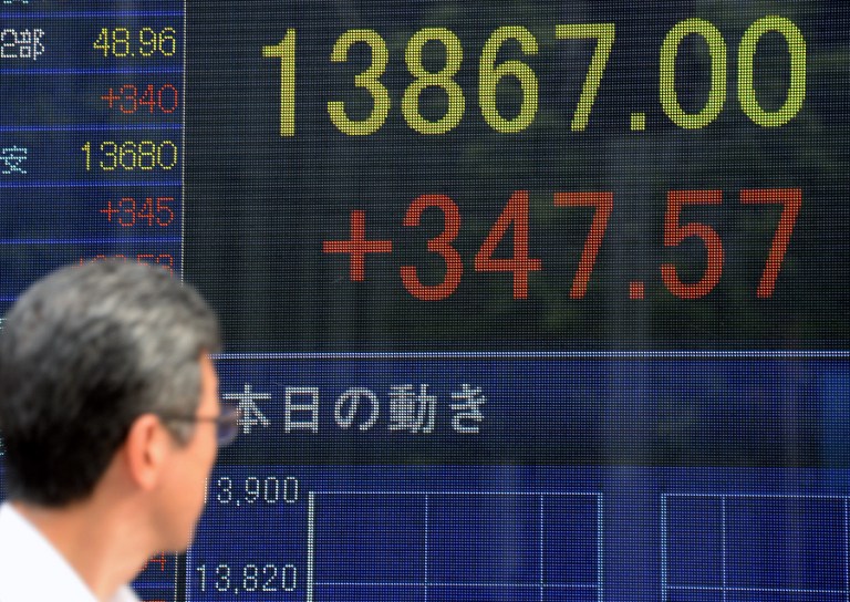 A pedestrian looks at the electric stock indicator in the window of a security company in Tokyo on August 13, 2013. u00e2u20acu201d AFP pic