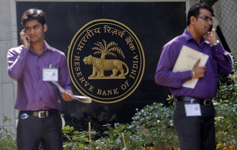 Two men make phone calls while standing near a Reserve Bank of India (RBI) crest at the RBI headquarters in Mumbai January 29, 2013. u00e2u20acu201d Reuters pic