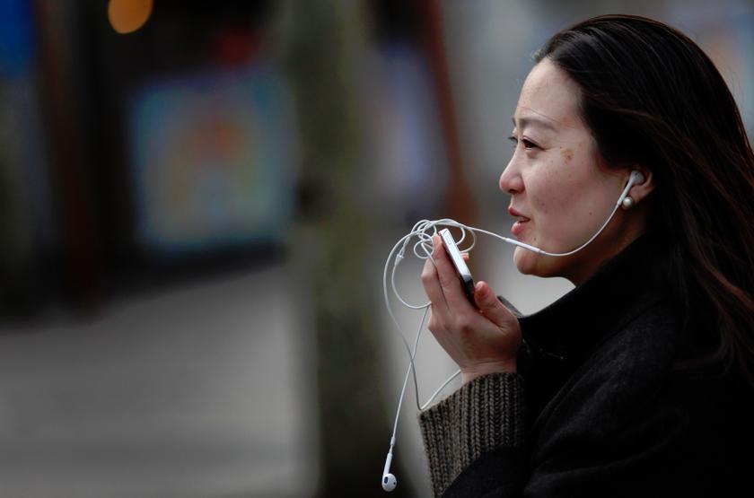 A woman speaks on her smartphone as she walks on a busy street in downtown Shanghai in this March 13, 2013 file photo. u00e2u20acu201d reuters pic