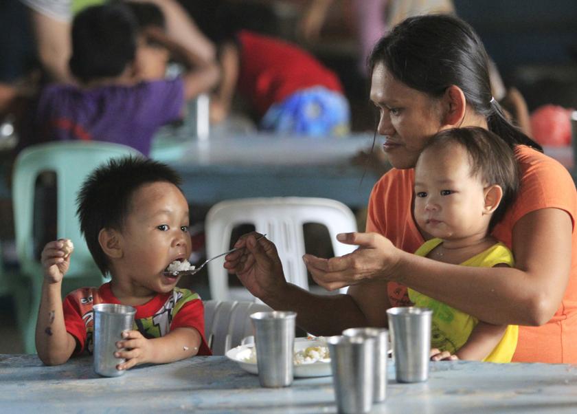 A mother divides a free meal between her children during a feeding program at a slum area in Baseco, Tondo, metro Manila January 20, 2014. u00e2u20acu201d Reuters pic