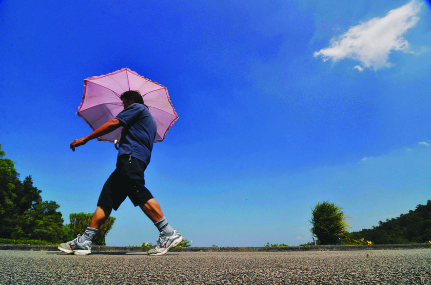 It's so hot, this man is using an umbrella while out for his evening walk at Air Itam Dam in Penang.
