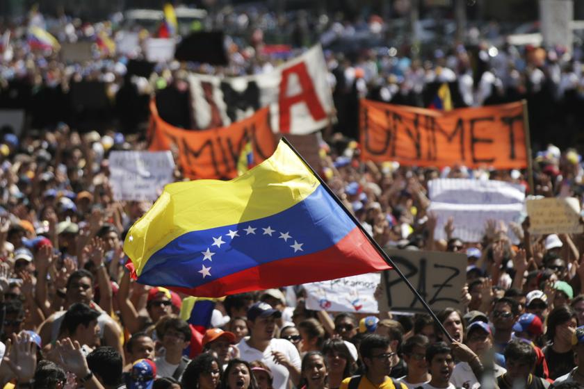 Demonstrators wave a Venezuelan flag as they march during an anti-government protest in Caracas, February 16, 2014. Protesters gathered to demand the resignation of Venezuelan President Nicolas Maduro, blaming him for complaints ranging from high inflatio