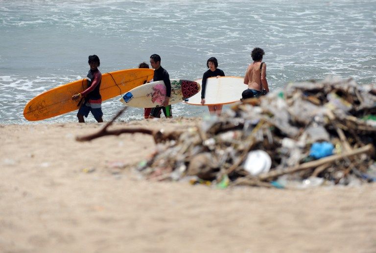 Foreign tourists walk past debris on Kuta beach near Denpasar on Bali island. u00e2u20acu201d AFP pic