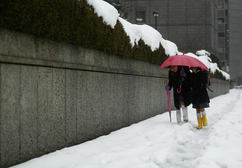 Schoolchildren share an umbrella on a street covered by snow near the Bank of Japan building in Tokyo February 15, 2014. u00e2u20acu201d Reuters