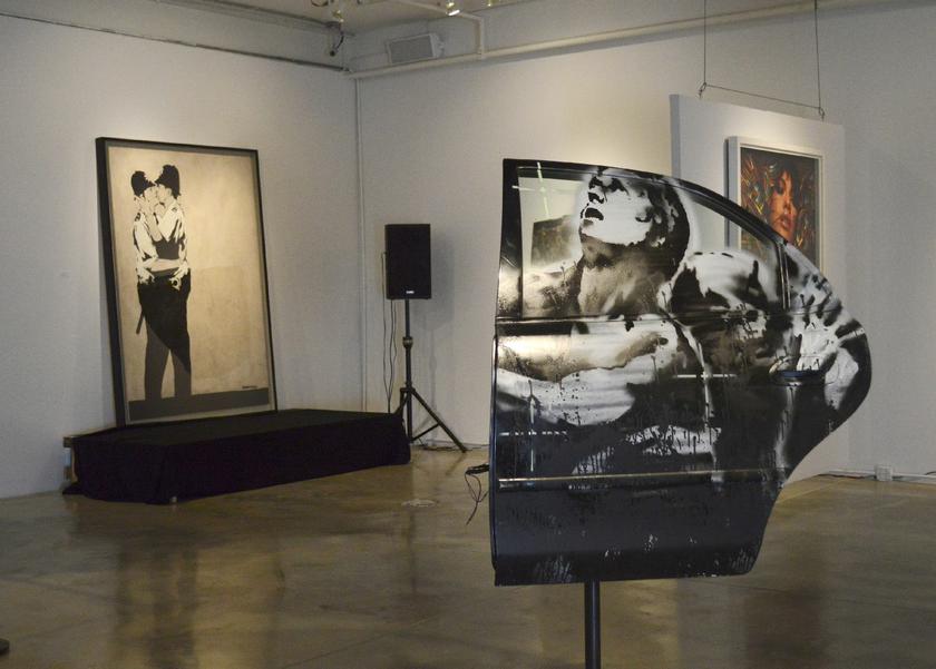 Paintings titled ,Crazy Horse Car Door, and in the background, ,Kissing Coppers,, by the British street artist Banksy, on display at LMNT Gallery in Miami, Florida February 18, 2014 Reuters