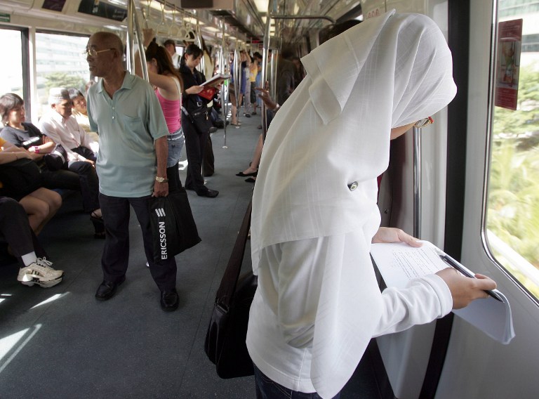 A Singaporean Muslim student checks through her papers on a MRT train in Singapore 03 January 2006. u00e2u20acu201d AFP pic