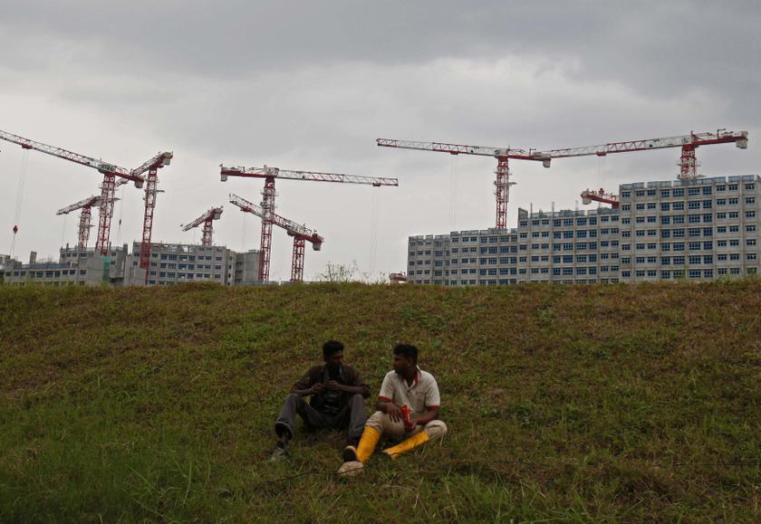 Migrant workers chat while taking a break on a grass field near a public housing construction site in Singapore January 23, 2014. u00e2u20acu201d Reuters pic