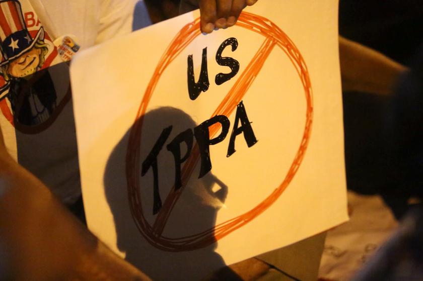 A protester holding a TPPA protest poster while sitting on the road at the entrance of Komplex Pejabat Kerajaan Jalan Duta, on February 13, 2014.. u00e2u20acu201d Picture by Choo Choy May