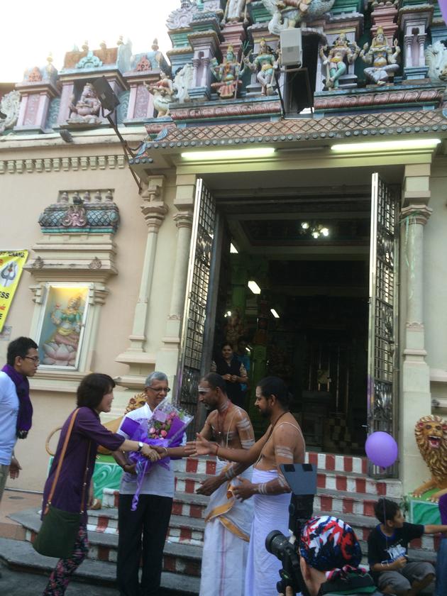 Jenny handing over the bouquet of flowers to Varatharajoo and shaking hands with the temple priests.