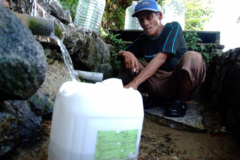 Jusli Ibrahim, 56, a villager from Kampung Sungai Katali fills containers with water from a hill source to meet his daily needs. u00e2u20acu201dPicture by Mohd Yusof Mat Isa