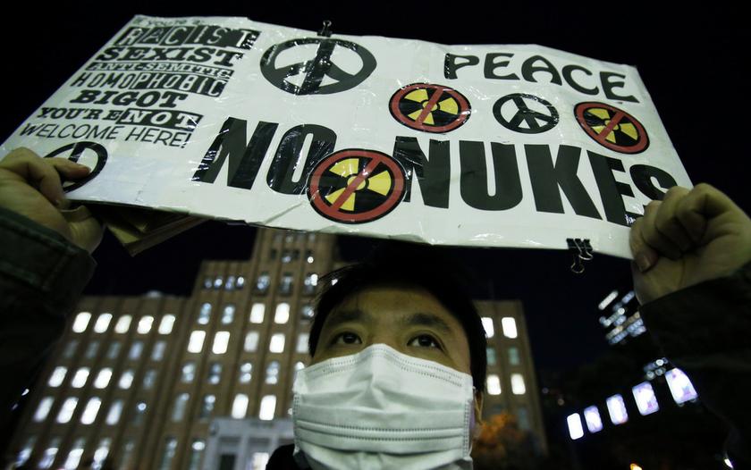 An anti-nuclear protester holds up a placard in front of a branch of Kansai Electric Power Co, the operator of the Ohi nuclear power plant which has been shut down, in Tokyo March 10, 2014, a day before the third anniversary of the March 11, 2011 earthqua