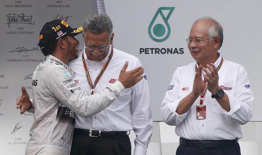 Race winner Mercedes Formula One driver Lewis Hamilton of Britain (left) is congratulated by President and Chief Executive Officer of Petronas, Shamsul Azhar Abbas, as Malaysia's Prime Minister Najib Razak (right) looks on.  u00e2u20acu201d Reuters pic