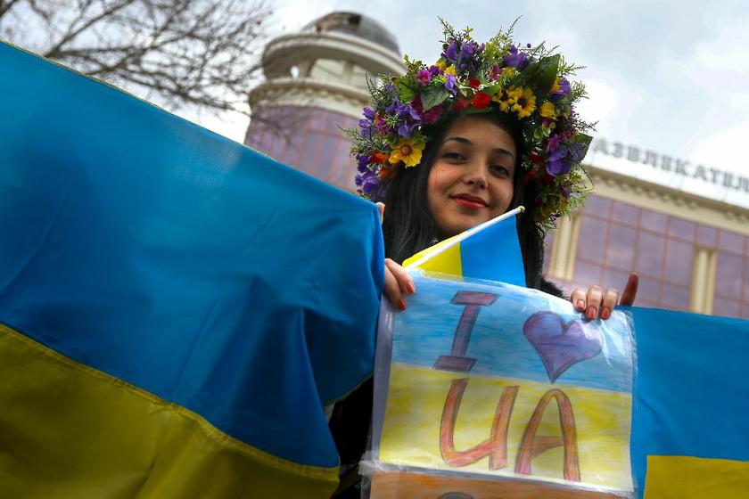 A pro-Ukraine protester wears a flower wreath as she holds the Ukrainian national flag during a march through the local parliament building in the Crimean city of Simferopol March 8, 2014 Reuters