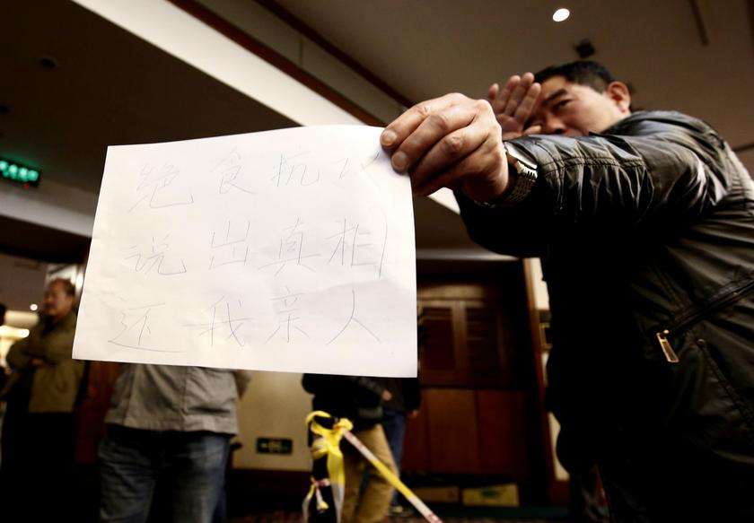 A relative of a passenger onboard the missing Malaysia Airlines Flight MH370 shows a paper with a message from family members at a hotel in Beijing March 18, 2014. u00e2u20acu201d Reuters pic